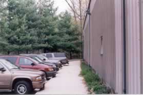 Turn left at the entrance to the building and follow the sidewalk along the edge of the building away from the entrance.