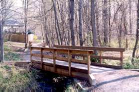 The trail crosses a bridge and passes the side of homes at the end of Windward Dr.