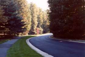 The path turns left onto the wide asphalt trail along the west side of North Village Rd.