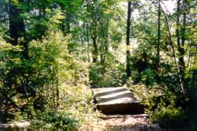 The path crosses a wooden bridge.  If you encounter a gravel section on the path you are on the road mentioned in 19 and must go back up the hill to the clearing.