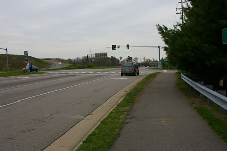 Follow the asphalt trail to the first traffic light. Turn left to cross Rolling Road.