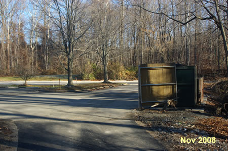 The trail enters the parking lot. Walk to the right until reaching the end of the lot, then turn left to follow the trail parallel to the access road.