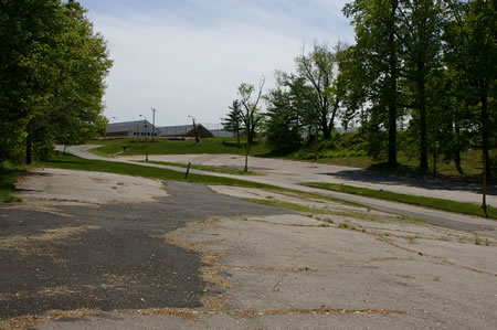 The trail leaves the woods and passes through a parking area next to the access road.