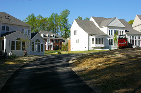 The trail leaves the woods and passes between the homes.