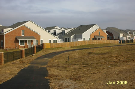 The trail goes down a hill and turns right to pass a gated community.