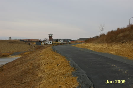 The trail follows the right edge of the retention basin.