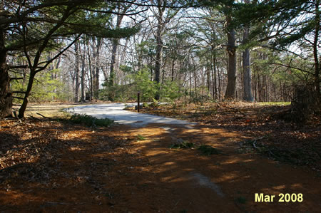 The trail turns to the right away from the road on the  left.