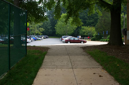 The trail reaches a parking lot. Turn left onto the sidewalk along the edge of the parking lot.