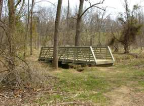 The trail leads to a bridge over a side stream.