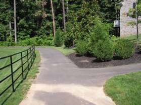 A trail intersects from the right between the houses.  Continue to the left along the main trail.