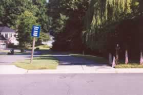 At the bottom of the hill as the road turns left cross the street to the asphalt path along the pipestem for 12016 Lake Newport Rd.