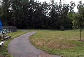 Continue on the sidewalk around the parking lot until reaching the asphalt trail at the end of the swimming pool. Turn left onto that trail.