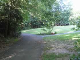 An asphalt trail intersects from the right. Continue straight on the present trail.