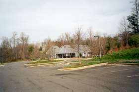 The asphalt trail becomes a concrete sidewalk.  Walk past the pool building.