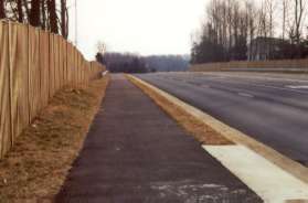 Wiehle Ave in this block is surrounded by fences on both sides.