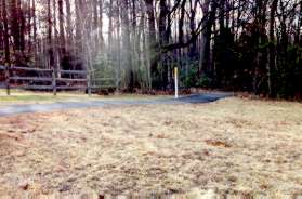 Near the top of the hill a fence blocks the pipeline trail.  The trail turns right and enters the woods.