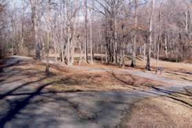 A gravel path intersects to the right leading to playground equipment.  Stay on the service road as it changes to a gravel surface.