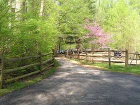 The trail passes a pond on the right with the Nature Center building on the left. Continue to the parking lot.